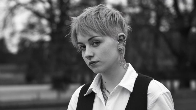 Person with short hair and multiple piercings.
