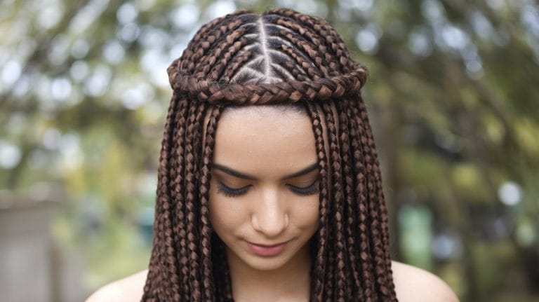 Woman with intricate brown braided hairstyle outdoors.