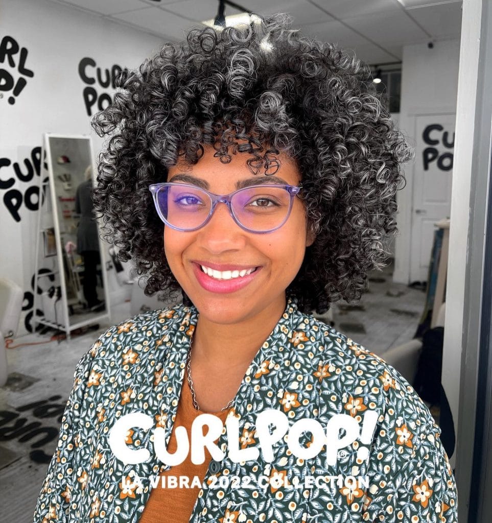 Smiling person with curly hair in salon.
