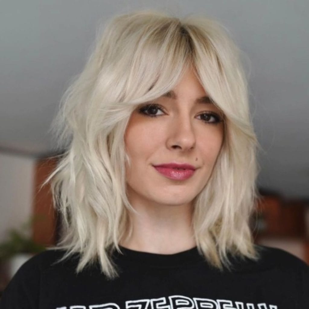 Smiling person with blonde hair and bangs.