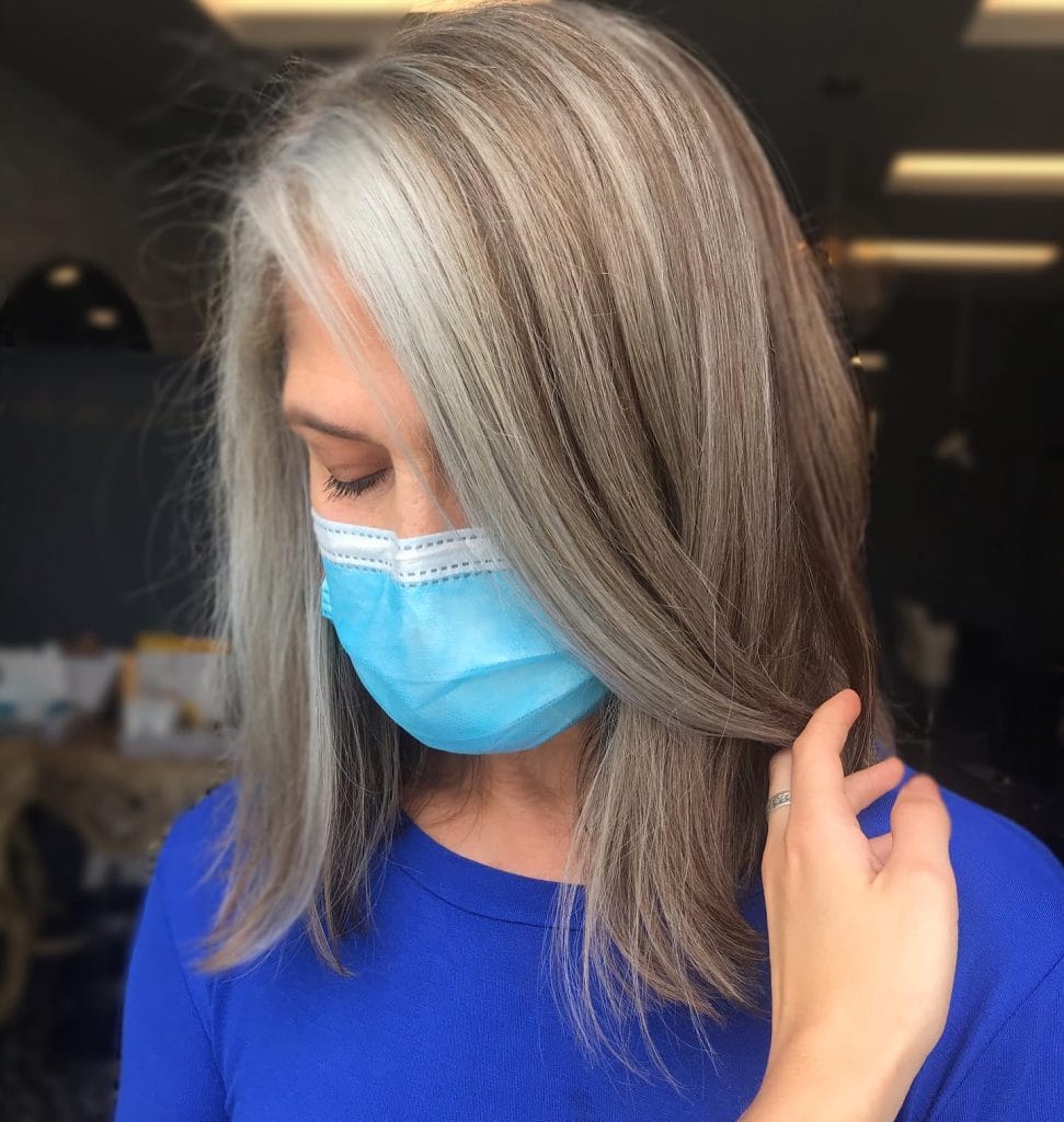 Woman with gray hair wearing blue mask indoors.