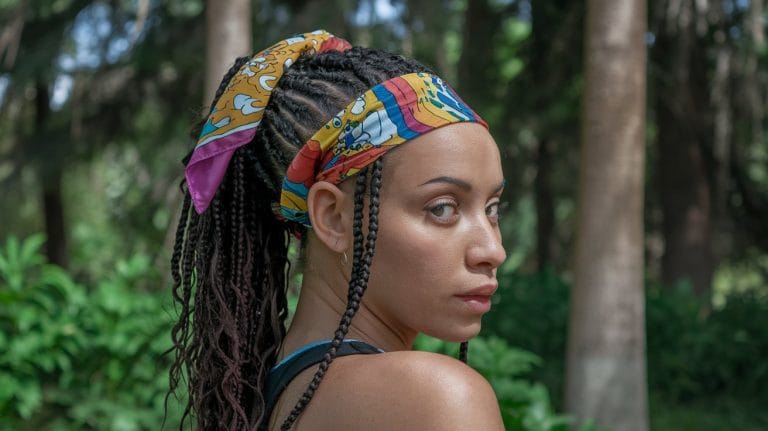 Woman with braided hair and colorful headscarf outdoors.