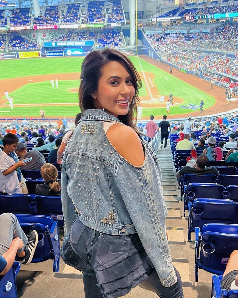 Woman smiling at baseball game in stadium.