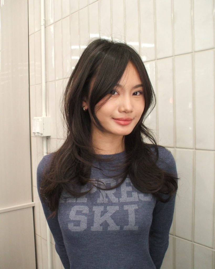 Woman in blue sweater against tiled wall.