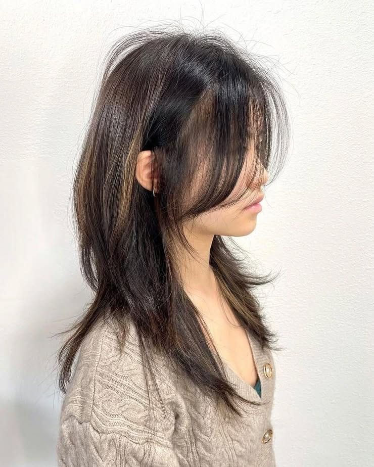 Woman with layered brunette hairstyle, side profile.