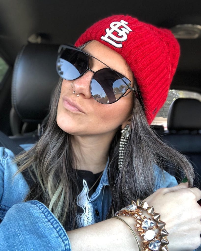 Woman in red beanie and sunglasses selfie.