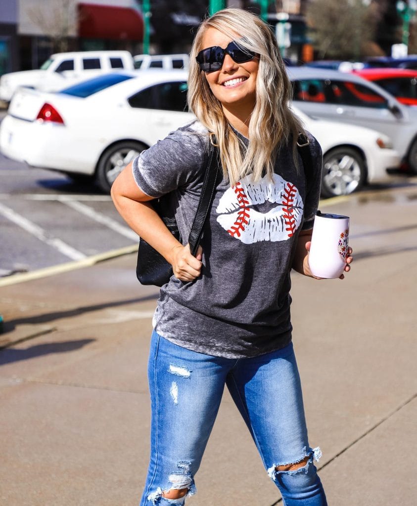 Woman smiling in casual streetwear holding a cup.