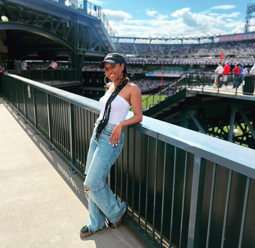 Woman posing at busy stadium on sunny day.